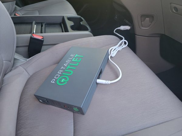 Photograph of Portable Outlet CPAP battery being charged on a car passenger seat